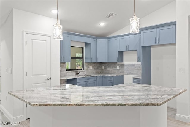 kitchen featuring pendant lighting, lofted ceiling, sink, and a kitchen island