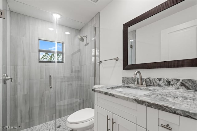 bathroom featuring vanity, toilet, and a shower with shower door