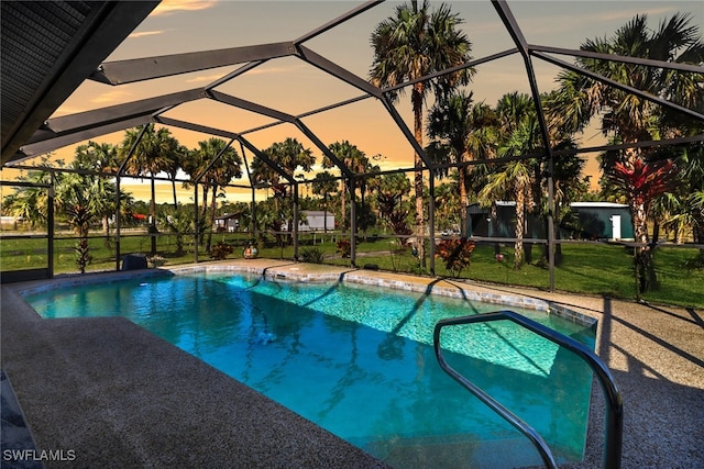 pool at dusk featuring a yard and glass enclosure