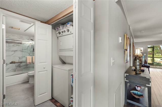 washroom featuring stacked washer and dryer and a textured ceiling