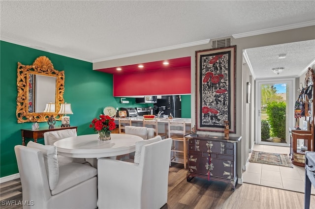 dining space with wood-type flooring, ornamental molding, and a textured ceiling