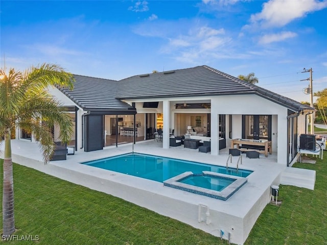 rear view of property featuring a swimming pool with hot tub, an outdoor hangout area, a yard, and a patio area