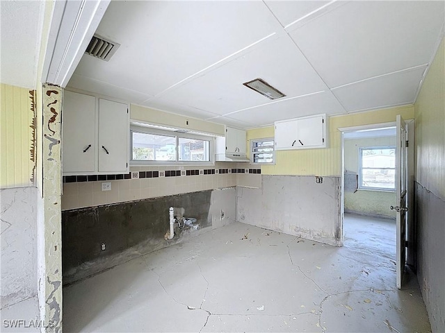 kitchen featuring concrete floors, plenty of natural light, visible vents, and white cabinets