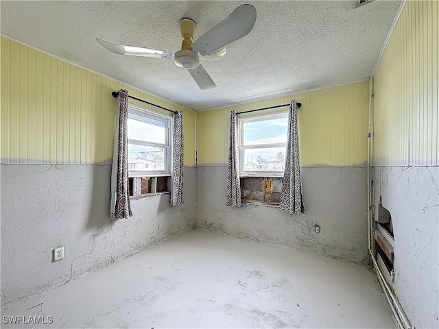 unfurnished room featuring ceiling fan, a textured ceiling, a wealth of natural light, and unfinished concrete floors