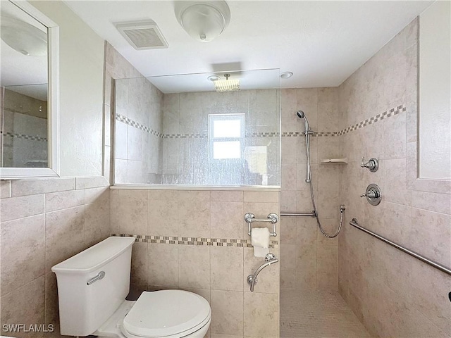 bathroom featuring toilet, visible vents, a tile shower, and tile walls