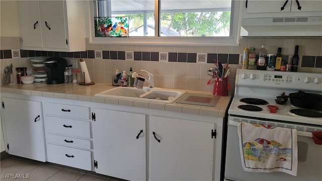 kitchen with tasteful backsplash, white electric range, white cabinets, light tile patterned flooring, and under cabinet range hood