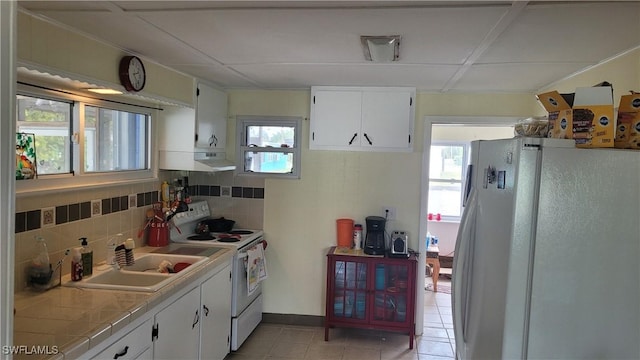 kitchen featuring tile countertops, white appliances, tasteful backsplash, and a wealth of natural light