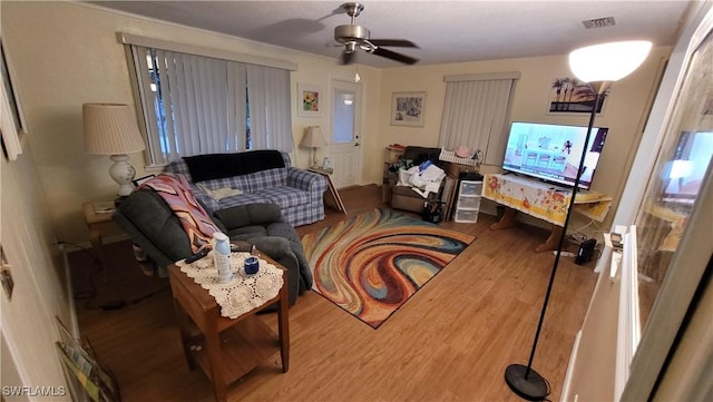 living area with visible vents, ceiling fan, and wood finished floors