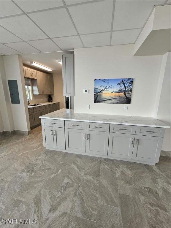 kitchen with a drop ceiling, gray cabinetry, and electric panel