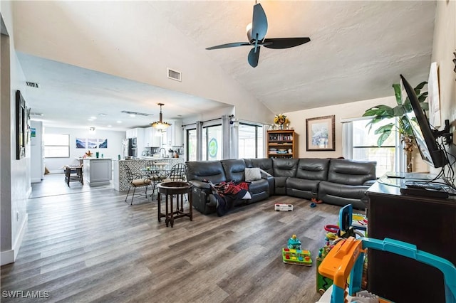 living room featuring hardwood / wood-style floors, a wealth of natural light, ceiling fan, and vaulted ceiling