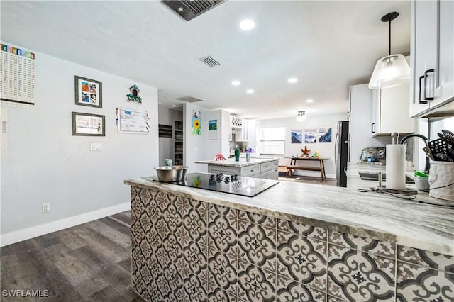 kitchen featuring light stone counters, stainless steel refrigerator, dark hardwood / wood-style flooring, pendant lighting, and white cabinets