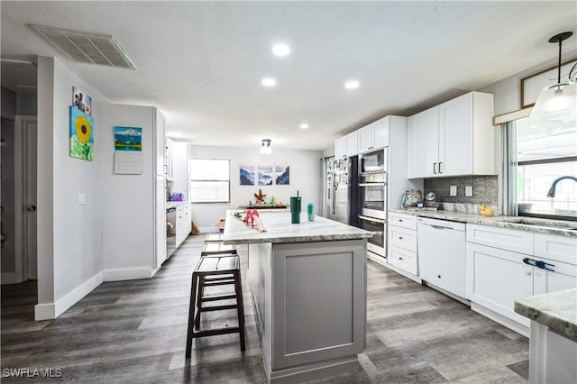 kitchen with dishwasher, sink, white cabinets, hanging light fixtures, and light stone counters