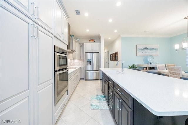 kitchen featuring pendant lighting, sink, a large island, stainless steel fridge, and white cabinetry