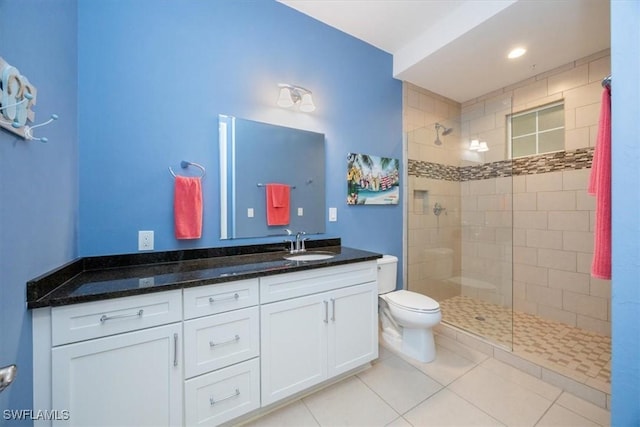 bathroom with vanity, tiled shower, tile patterned floors, and toilet