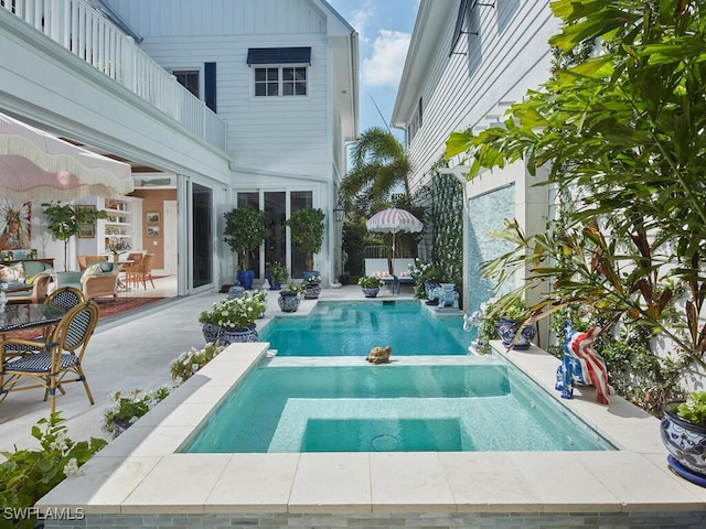 pool with a patio area and an in ground hot tub