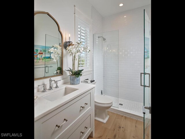 bathroom with a stall shower, vanity, toilet, and wood finished floors