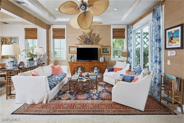 living area with ceiling fan, a raised ceiling, and visible vents