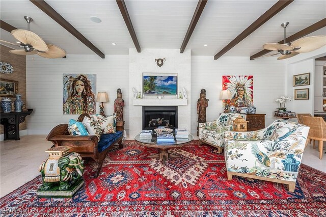 living room featuring a ceiling fan, a fireplace, and beamed ceiling