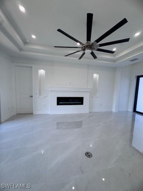 unfurnished living room with ceiling fan and a raised ceiling