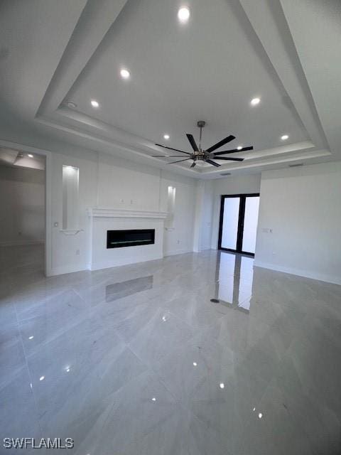 unfurnished living room with a raised ceiling and ceiling fan