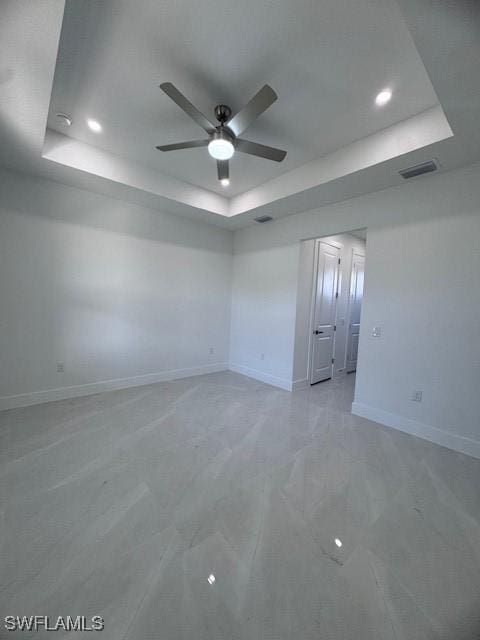 spare room with a raised ceiling and ceiling fan