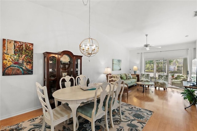 dining room with high vaulted ceiling, ceiling fan with notable chandelier, and light wood-type flooring