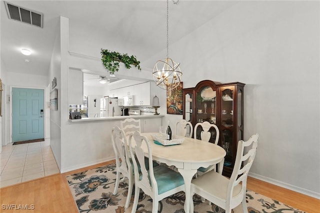 dining area with ceiling fan with notable chandelier and light hardwood / wood-style floors