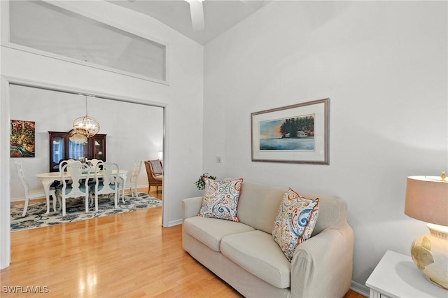 living room with hardwood / wood-style flooring, vaulted ceiling, and a chandelier