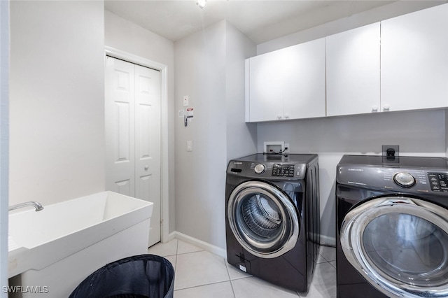 clothes washing area with cabinets, light tile patterned floors, and washer and clothes dryer