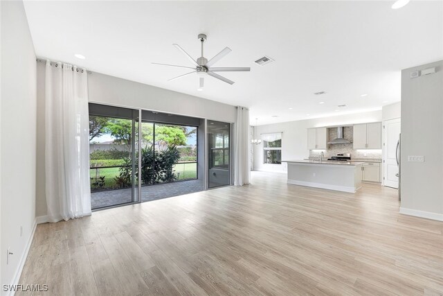 unfurnished living room with sink, ceiling fan, and light hardwood / wood-style flooring