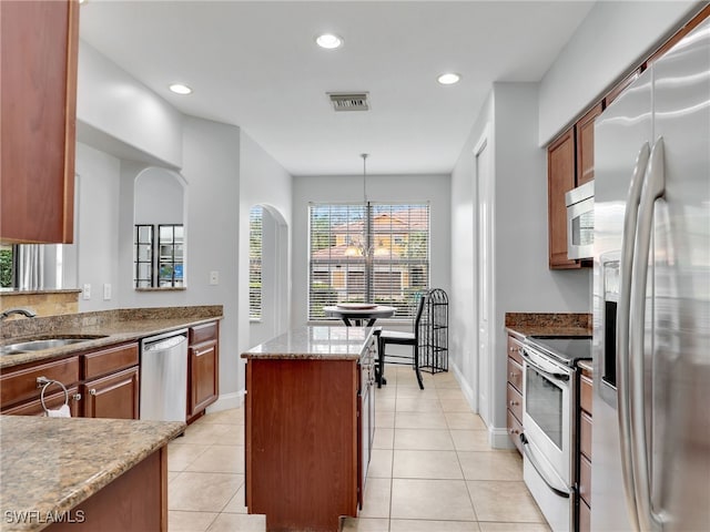 kitchen with pendant lighting, sink, light tile patterned floors, appliances with stainless steel finishes, and a kitchen island