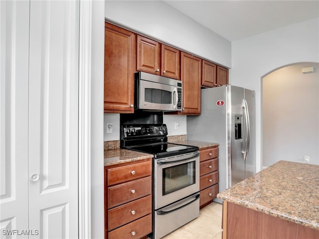 kitchen with light tile patterned flooring, appliances with stainless steel finishes, and light stone counters