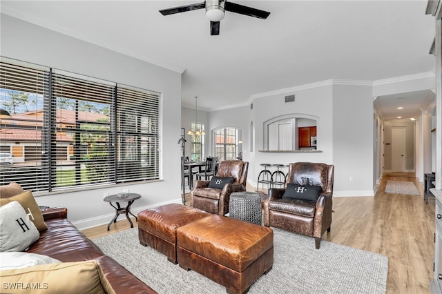 living room featuring ornamental molding, ceiling fan with notable chandelier, and light hardwood / wood-style floors