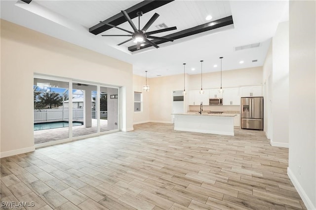 unfurnished living room with sink, ceiling fan, and a towering ceiling