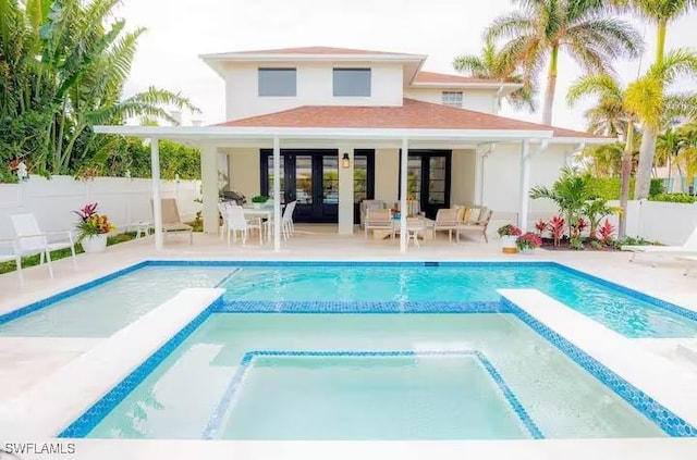 back of house with a pool with hot tub, an outbuilding, and a patio area