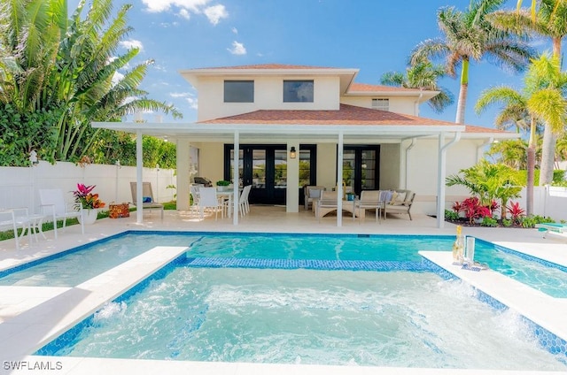 rear view of property with a fenced in pool, a patio area, and french doors