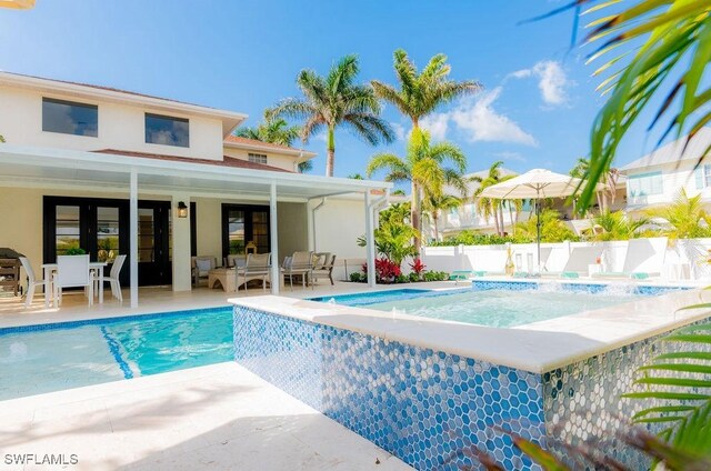 view of pool featuring french doors, pool water feature, and a patio area