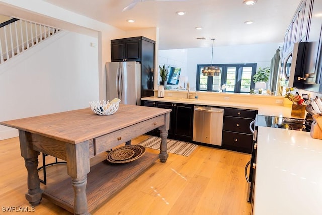 kitchen with hanging light fixtures, sink, light hardwood / wood-style floors, and stainless steel appliances