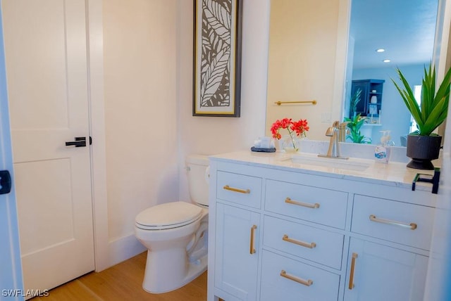 bathroom with hardwood / wood-style flooring, vanity, and toilet