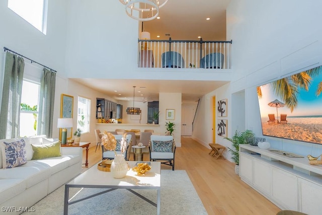 living room with a high ceiling, a chandelier, and light hardwood / wood-style floors