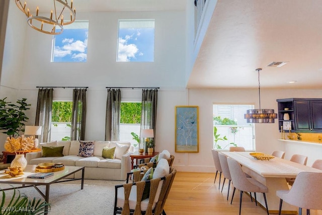 living room with plenty of natural light, light hardwood / wood-style flooring, and a notable chandelier