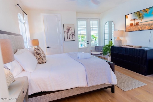 bedroom featuring multiple windows, french doors, and light hardwood / wood-style flooring