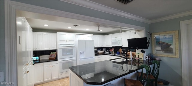 kitchen featuring white appliances, ornamental molding, white cabinets, a kitchen bar, and kitchen peninsula