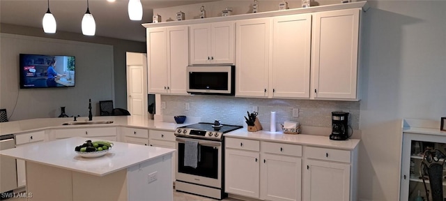 kitchen with pendant lighting, sink, appliances with stainless steel finishes, white cabinetry, and kitchen peninsula