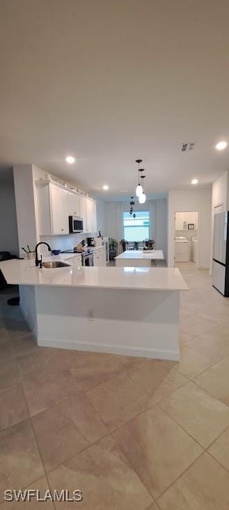 kitchen with sink, white cabinetry, white refrigerator, pendant lighting, and washing machine and dryer