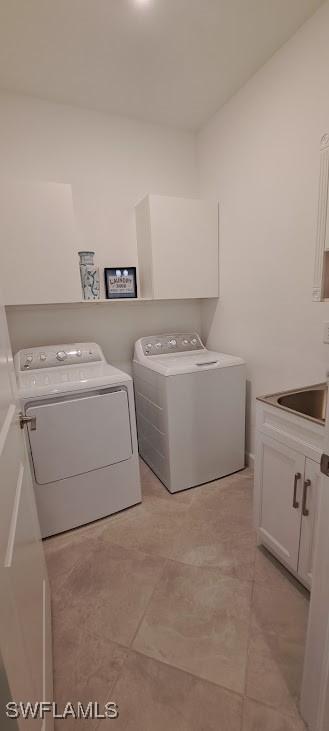 washroom with sink, washing machine and dryer, and cabinets