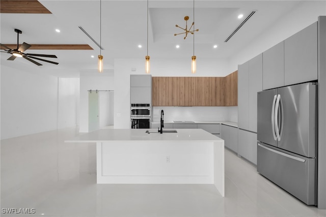 kitchen featuring sink, appliances with stainless steel finishes, pendant lighting, ceiling fan, and a large island