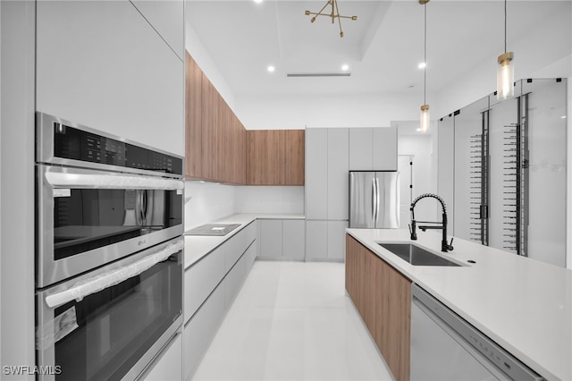 kitchen with pendant lighting, stainless steel appliances, sink, and white cabinets