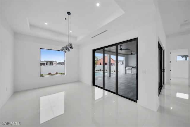 tiled empty room featuring a tray ceiling