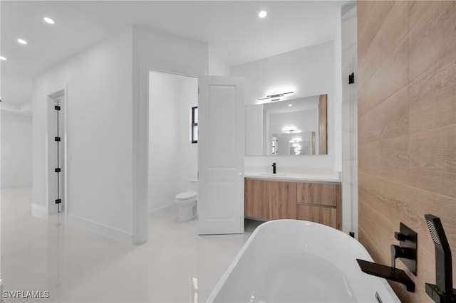 bathroom featuring a washtub, vanity, and toilet